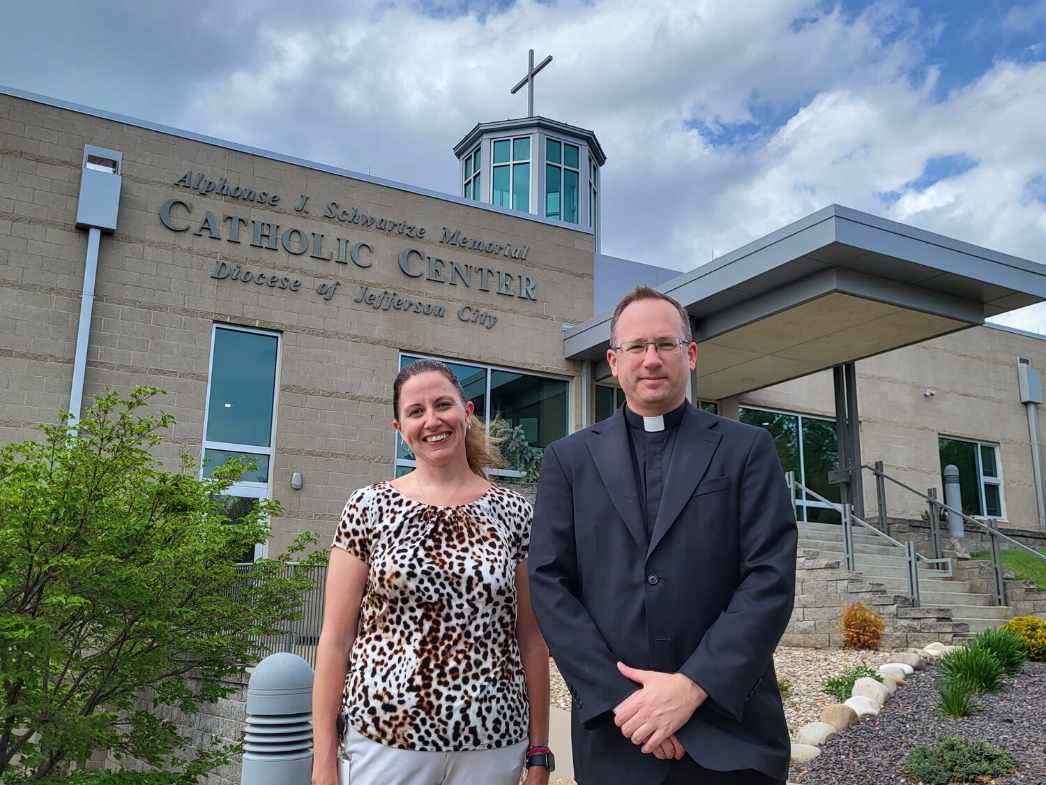 Danielle Freie joins her former pastor, Father Jason Doke, moderator of the curia for the Jefferson City diocese and one of the many priests she maintains regular contact with to help them advocate for their health and wellbeing, outside the Alphonse J. Schwartze Memorial Catholic Center in Jefferson City.